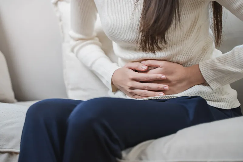 Close up of person holding their stomach, implying a stomach ache