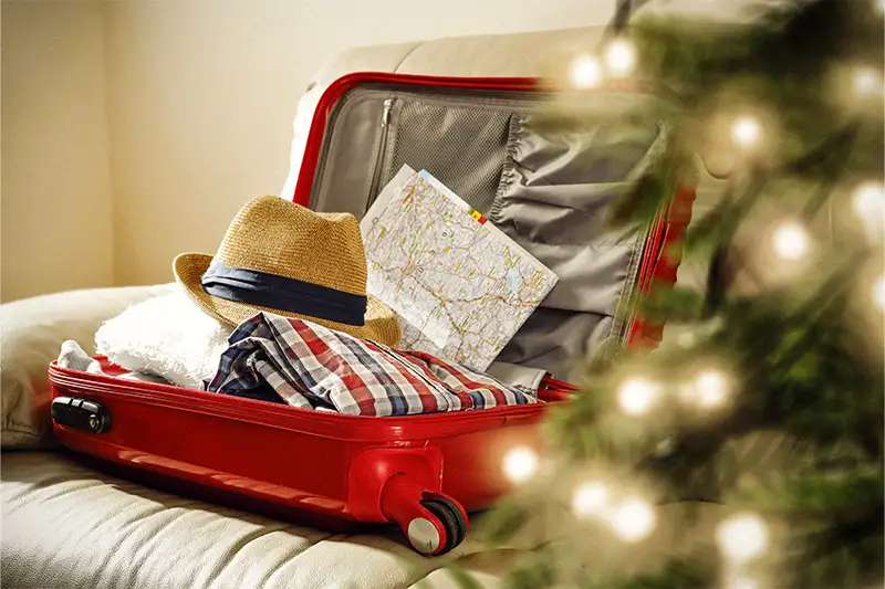 Suitcase full of clothes, sitting on a couch next to a Christmas tree