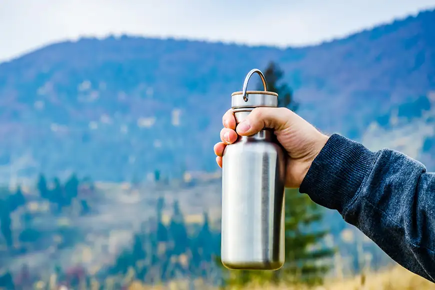 Man holding a bottle on the carpathian mountains background