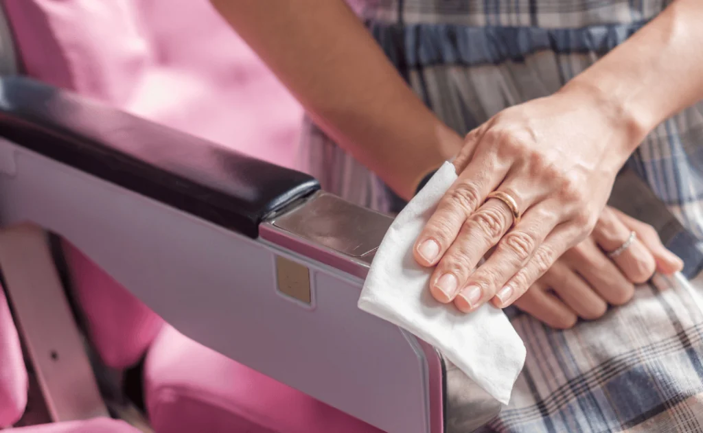 Woman cleaning the armrest of a seat with a wet wipe