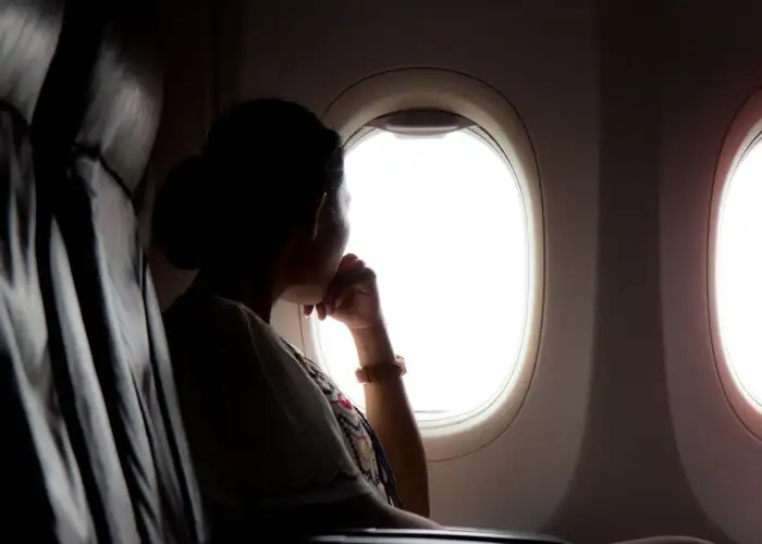 woman looking out airplane window.