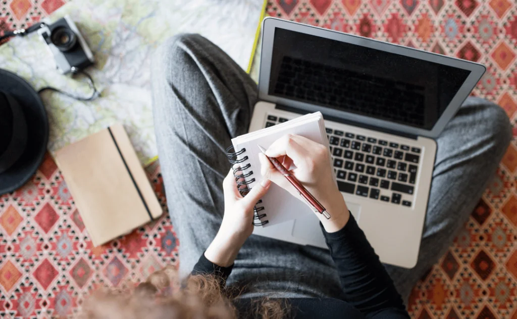 Woman planning staycation on the computer and writing notes