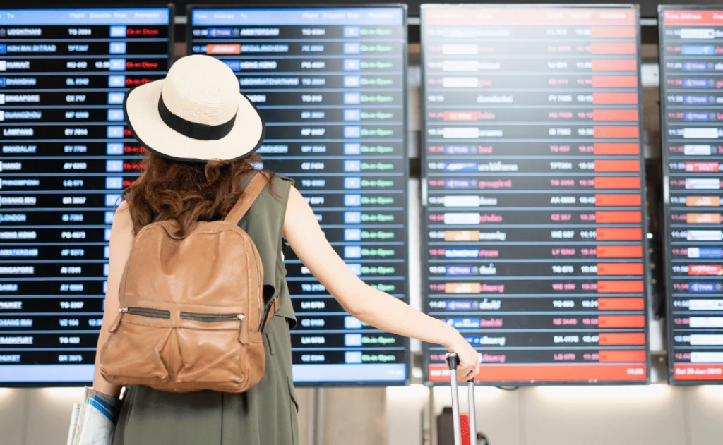 Woman traveler checkig the Boarding and Departure times shown on big screens at the airport