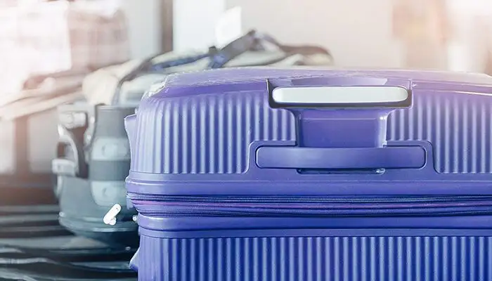 Hardside blue suitcase coming down the conveyor belt at baggage claim