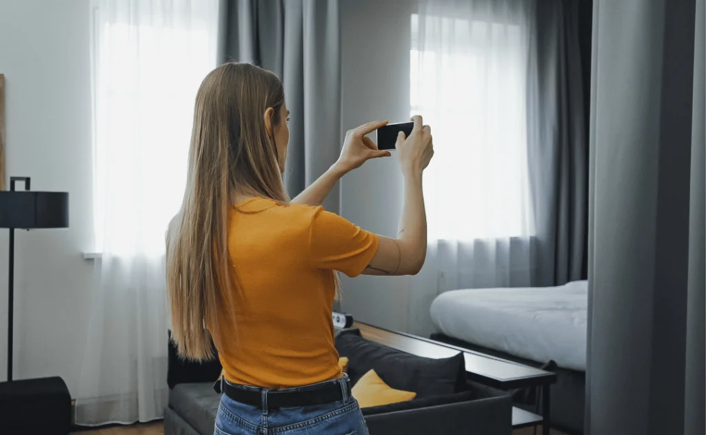 young traveler taking photo of hotel room on smartphone